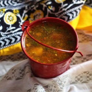 close up of rasam recipe in a red bucket