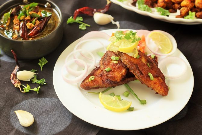 pomfret fish fry recipe in a white plate garnished with coriander leaves, lemon wedges