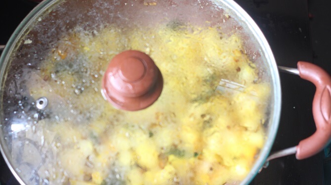 potato poriyal getting cooked with glass lid covered