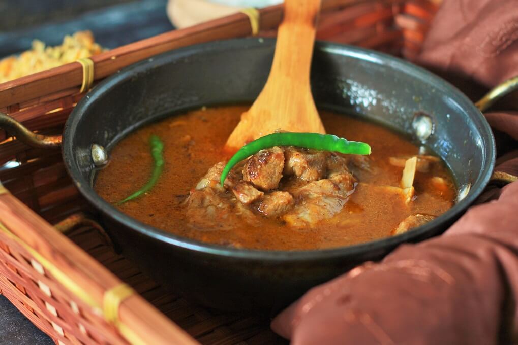 Mutton-Masala-Recipe with a wooden spoon in a kadai