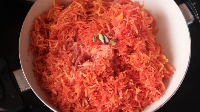 grated carrots, cardamom in a white pan