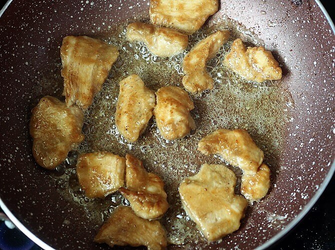 frying the chicken pieces in oil in a pink pan
