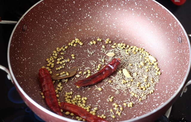 roasting spices in a pink kadai