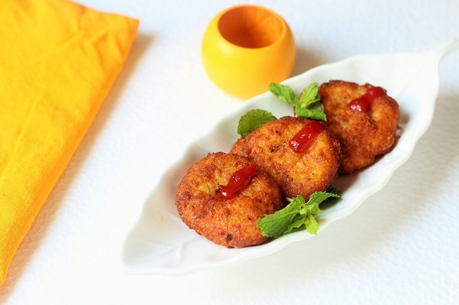 aloo ki tikki in a white plate with ketchup on top