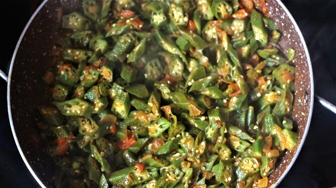 bhindi masala recipe being prepared in a pink pan