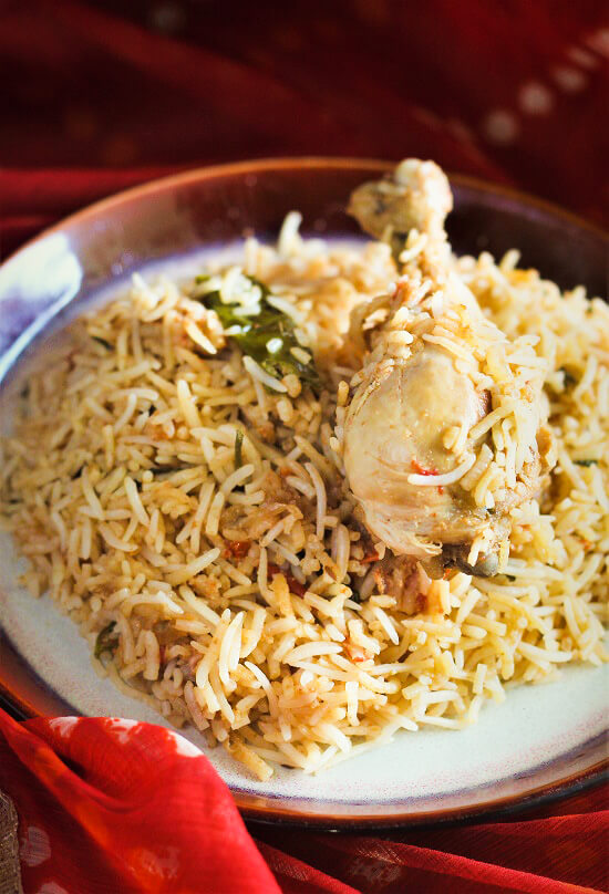 south indian chicken biryani served in a plate with chicken leg on top