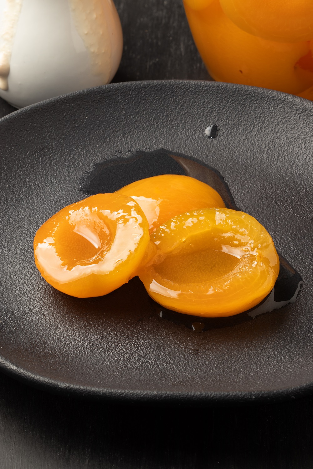 Canned peaches in a black plate.