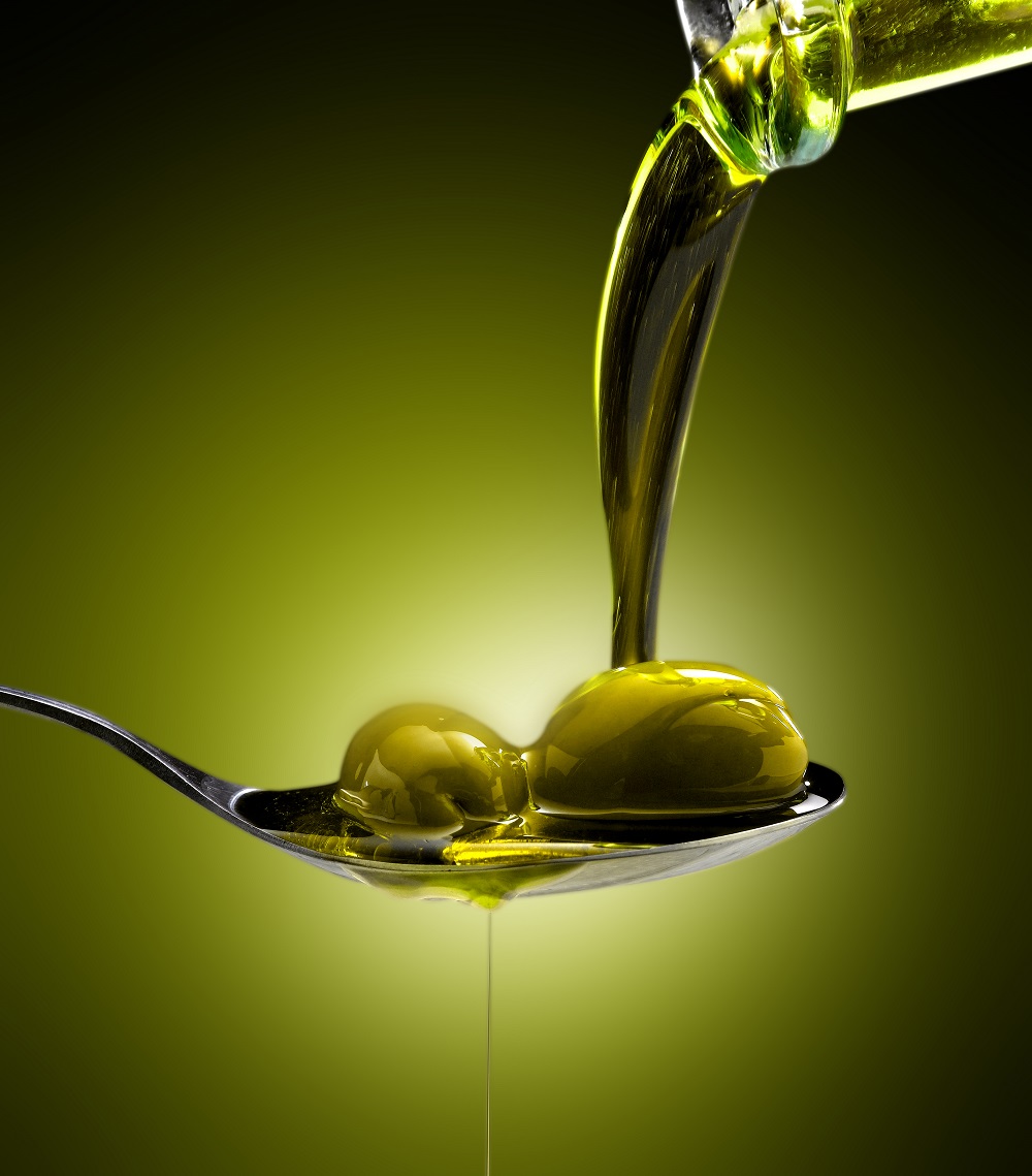 close-up-olive-oil-poured-into-spoon-olives