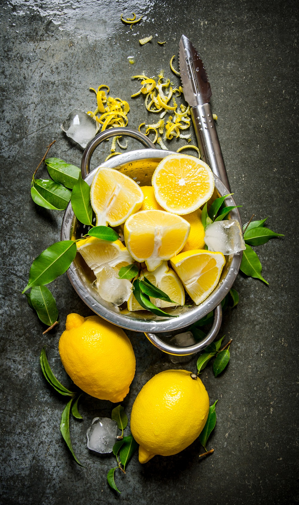 Fresh lemons in a saucepan with leaves and zest.